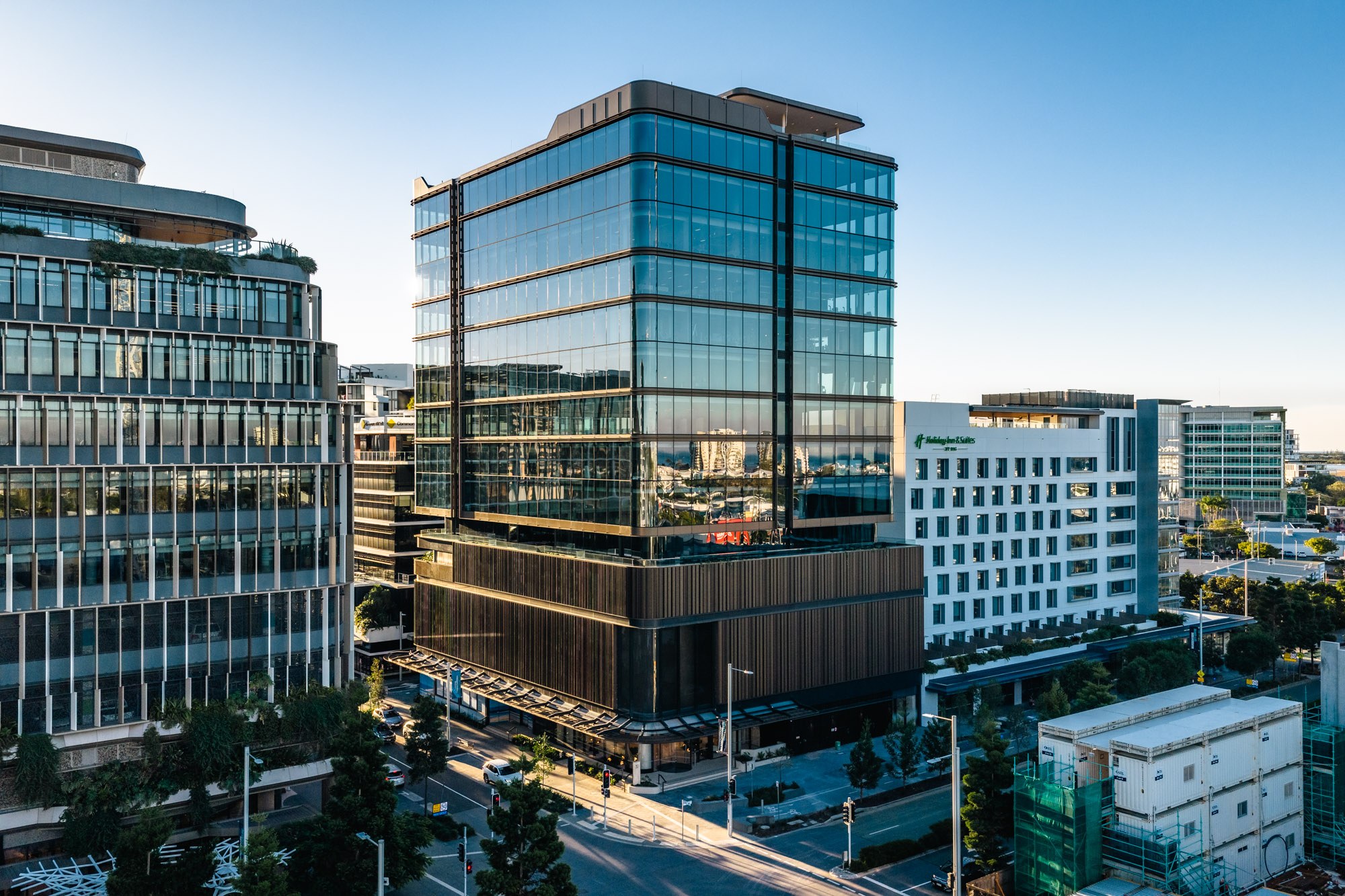 Modern glass and steel office buildings in a downtown urban district under clear blue sky, featuring contemporary architecture with reflective windows.