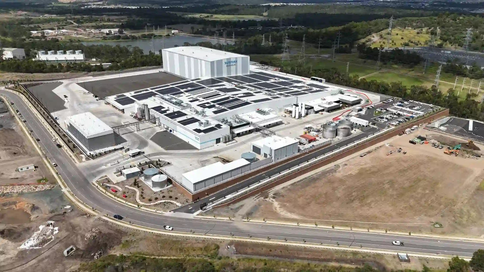 Aerial view of Surtopy Ostara facility with solar panels on roof, surrounded by roads, industrial buildings, and green landscape.
